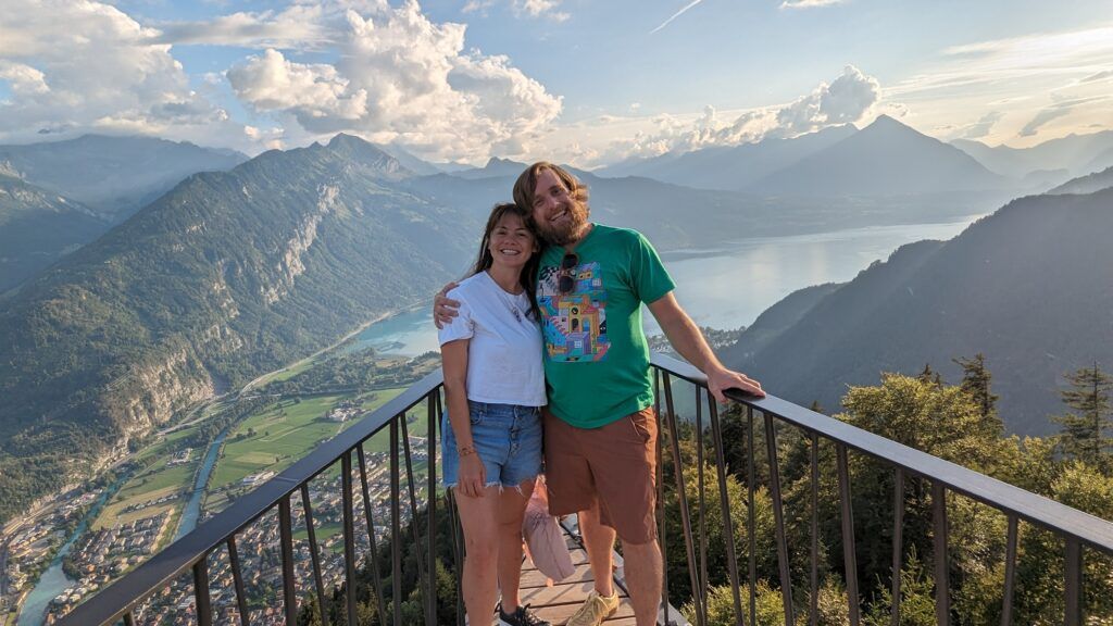 Brad and Melissa posing for a photo with a beautiful Swiss mountain vista and lake behind them.