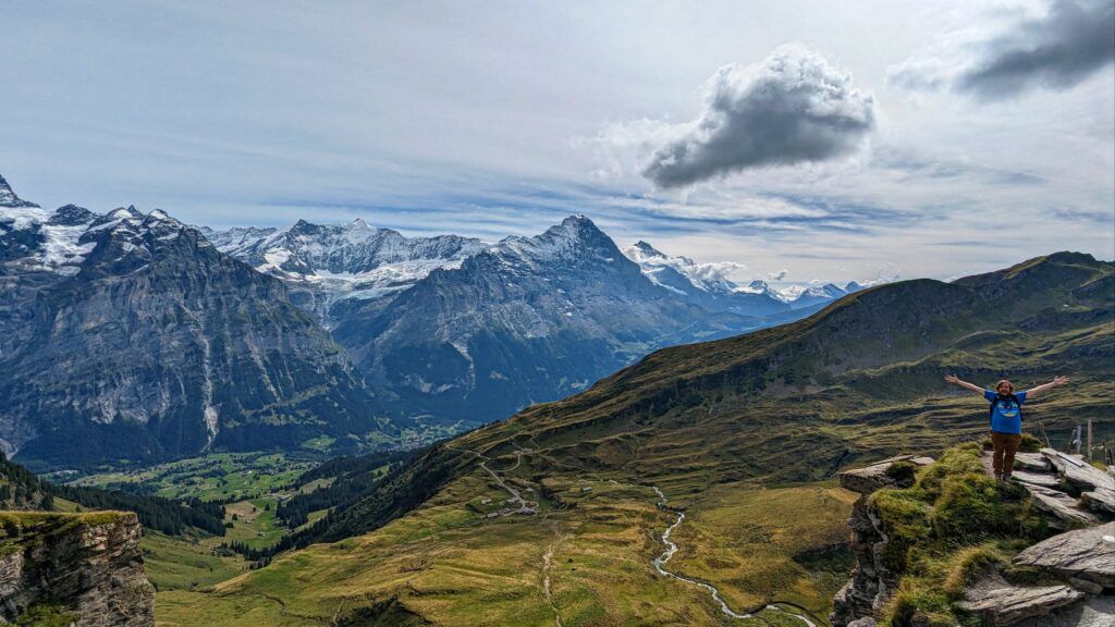 Brad standing with outreached arms with the huge Swiss Alps in the background