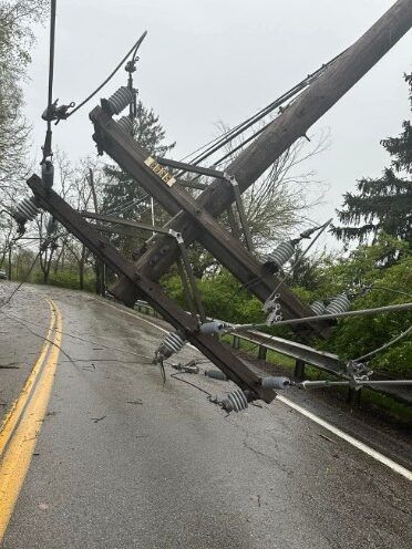 A downed telephone pole dangerously hanging over a road