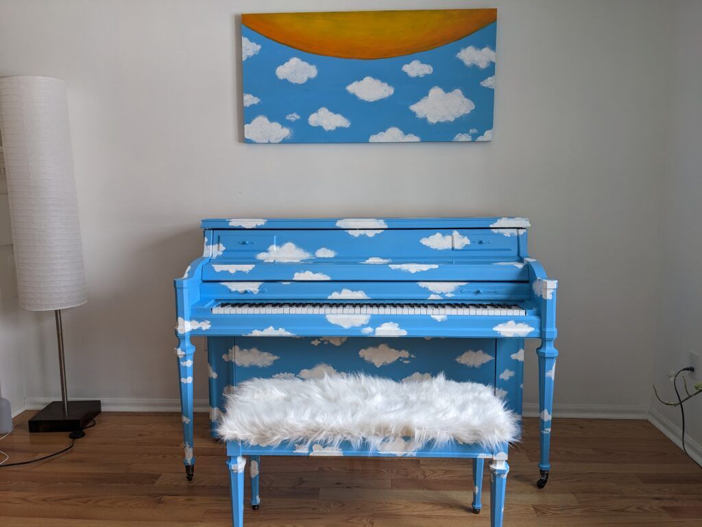 A piano painted sky blue with puffy white cloud pattern